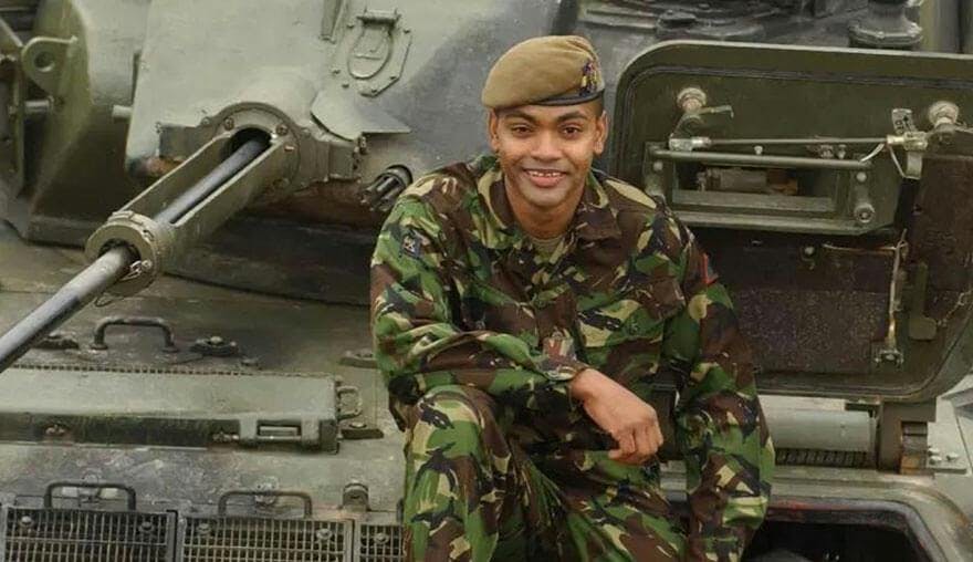 Johnson Beharry sat on top of a military vehicle 