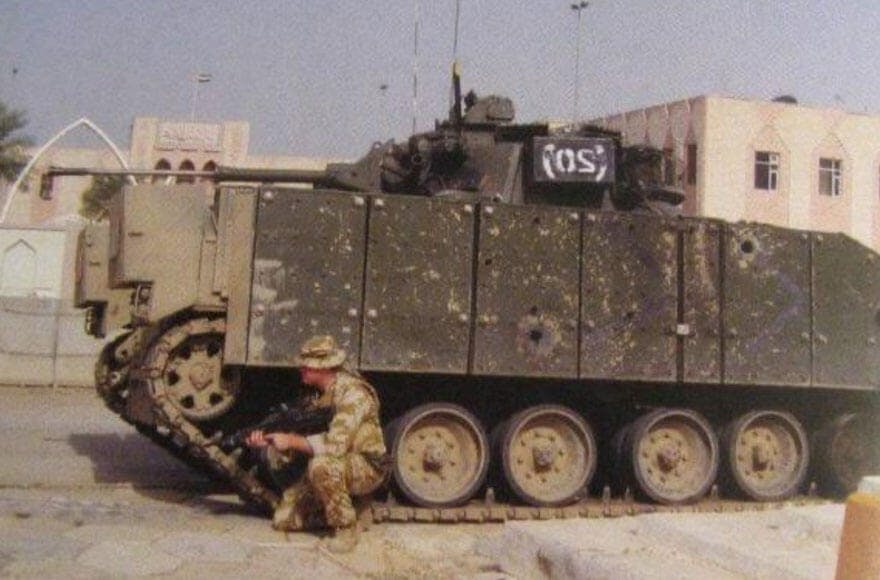 Johnson Beharry crouched by a tank 